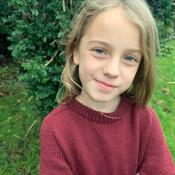 Striksweater til børn. Sandness klompelompe i farven dyb julerød, perfekt julsweater