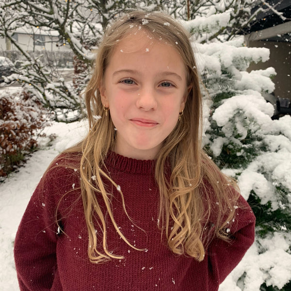 Striksweater til børn. Sandness klompelompe i farven dyb julerød, perfekt julsweater. Strikkeopskrift fra AlmaKnit.