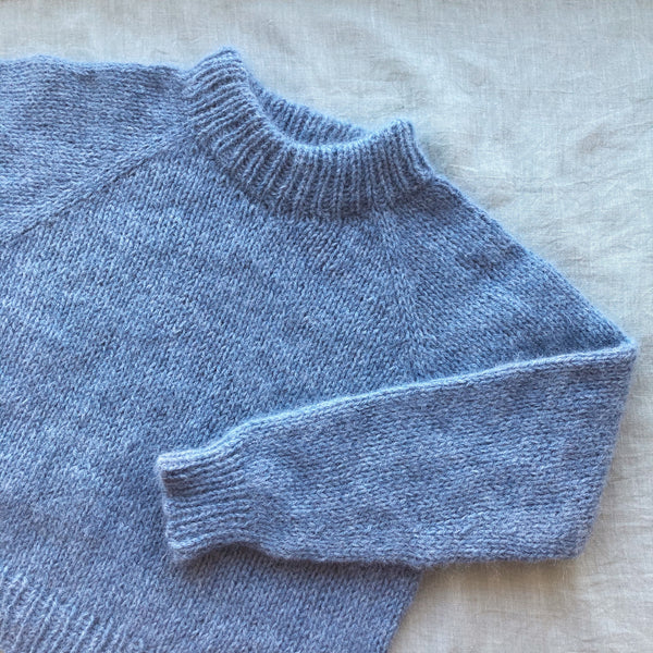 To plus to sweater. Børnestrik. Striktrøje med ombukket halskant strikket i oenling no 1 i farven dueblå. Strikkeopskrift fra AlmaKnit